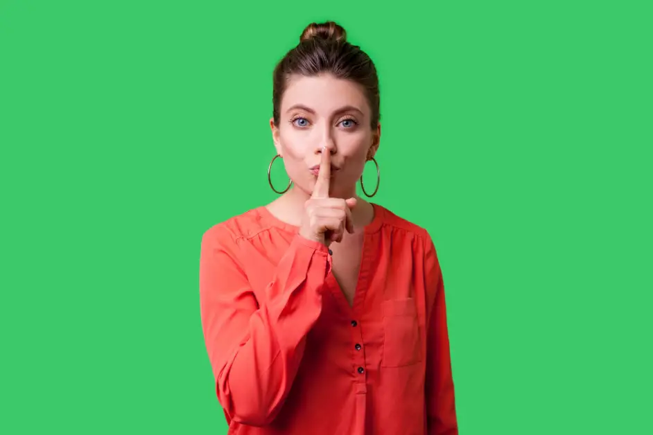Funny Mom Lies that will make you laugh. Picture of a Mom making the silence sign with her finger to her mouth with green background