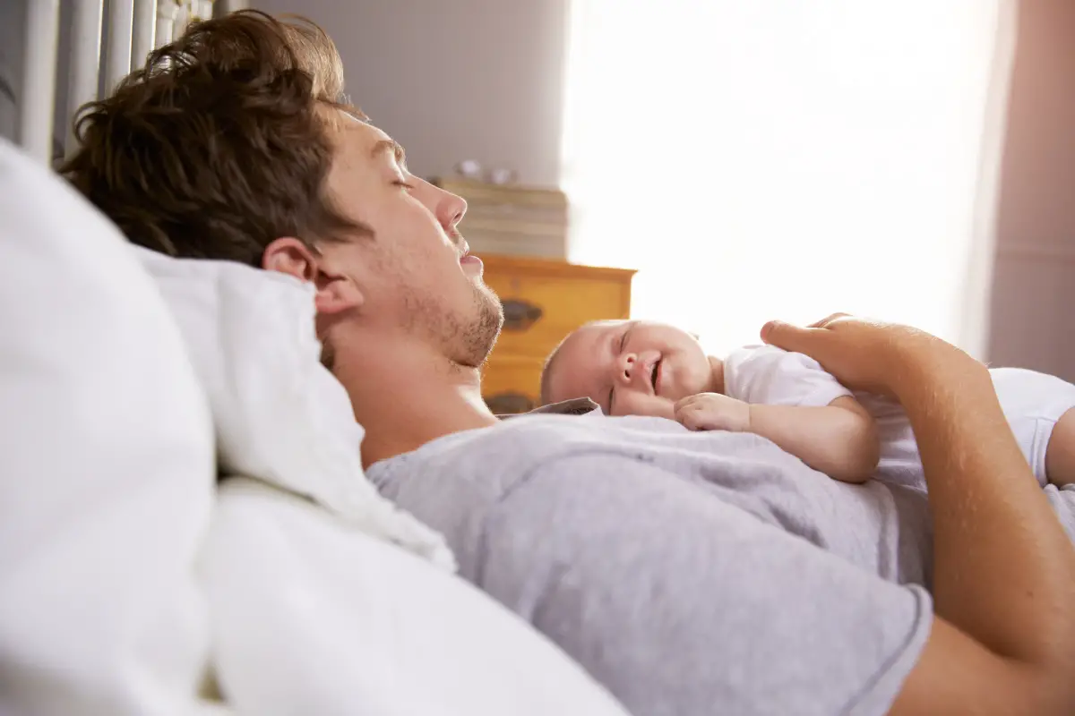 New Father laying with baby on chest sleeping - Best Pregnancy Books for Dads