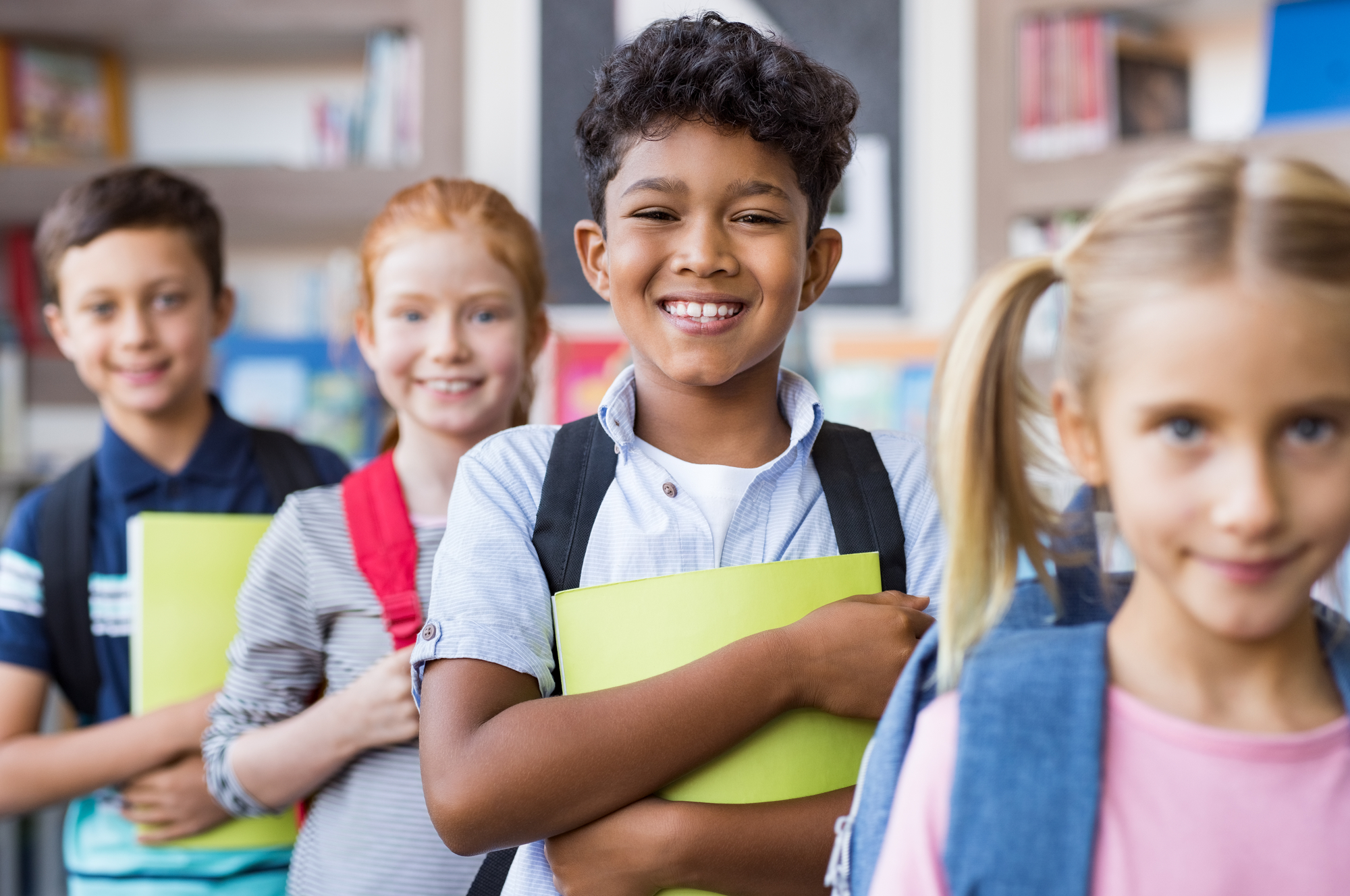 Happy multiethnic children holding books and wearing backpacks - How Old Are You In 4th Grade